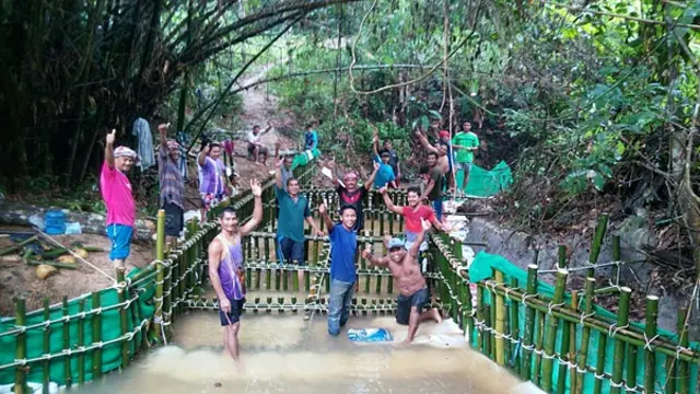 Men posing for a photo while constructing a weir with bamboo structures.