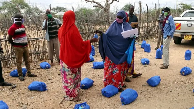 A woman hands protective equipment to another woman.