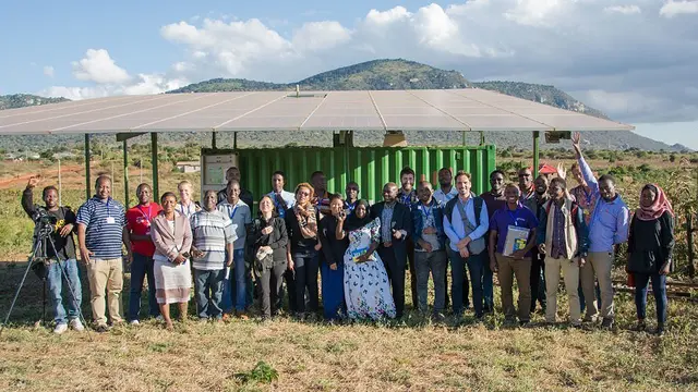 A group of people line up in front of a mountain background.