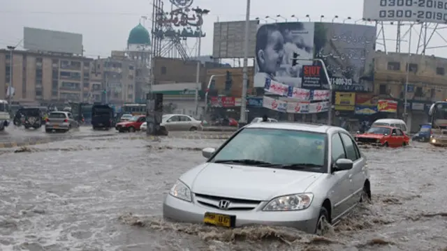 Car driving through a heavily flooded road.