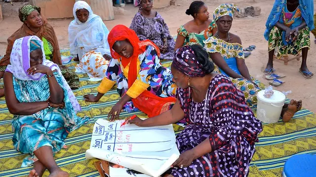 A group of women writing notes on a poster.