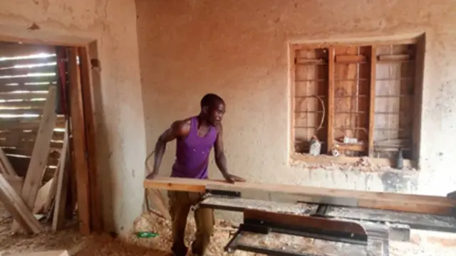 A carpenter uses a jointer powered by a mini-grid