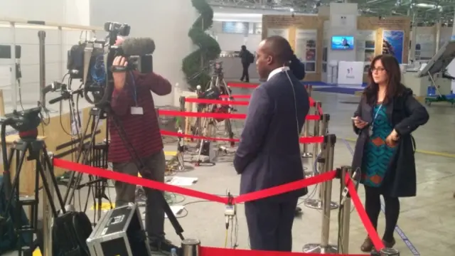 Man surrounded by cameras being interviewed in a cordoned-off area