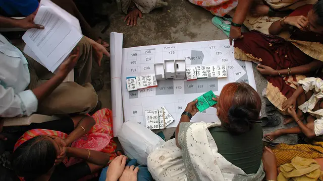 People sit on the floor around a map laid out on the floor
