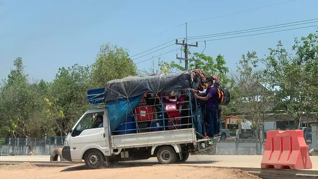 Pick-up van packed with people and suitcases.