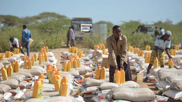 Piles of bags and jerrycans. Men pick some of them up. 