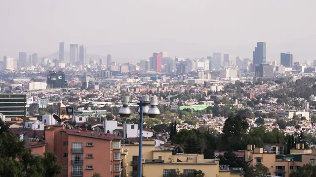 Skyline view of a city with houses and short buildings in the front and skyscrapers in the background.