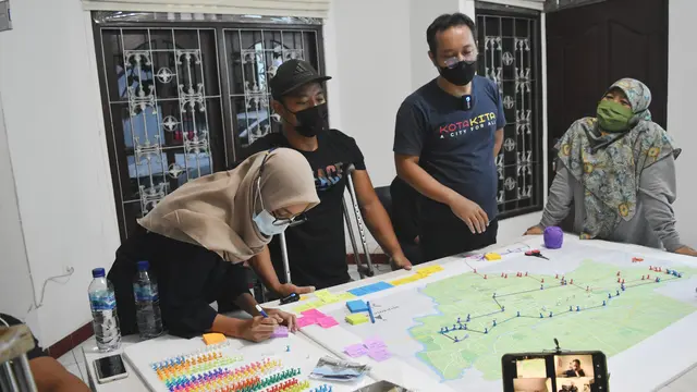 A group of people stand around a map on a table.