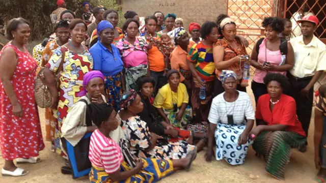 A group of women gather round the entrance to a building.