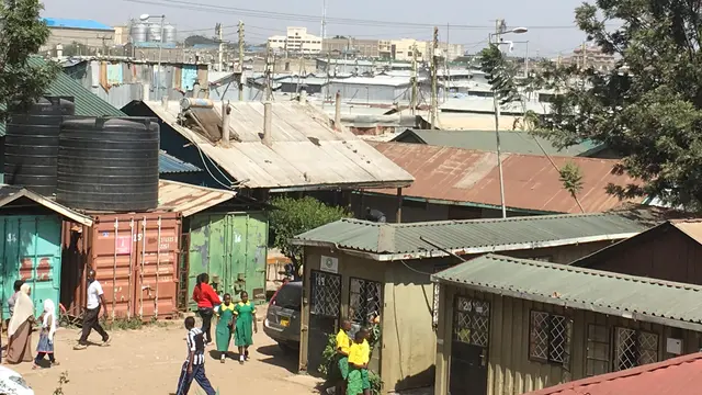 A busy African street scene, with industrial buildings in the background.