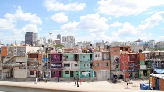 In the foreground, a hotchpotch of buildings close together, towered over by large buildings in the background.