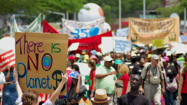 A young person holds up a sign, saying "There is no planet B" among a march