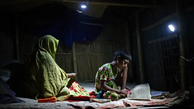 A girl studies under the light of a rechargeable solar lamp.