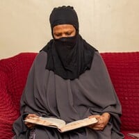 Woman sitting on a couch reading a book. 