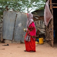 Woman standing on dirt ground.