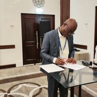 A man signs a piece of paper in fron of two other people.