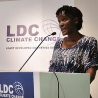 Vanessa Nakate speaking behind a podium.