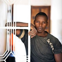 A man standing in front of a gate, gazing outside.