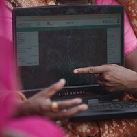 Close up of a women pointing at a laptop's screen.