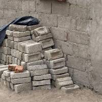 Grey bricks piled up outside a wall built of the same material.
