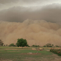 A giant dust storm dominates the horizon, with fields in the foreground.
