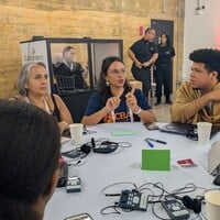 People sitting down at a round table, discussing and writing down ideas.
