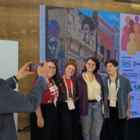 Group of four session leads standing in front of the CBA19 logo, having their picture taken by a firth person.