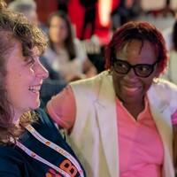 Two women sitting down, laughing and talking.