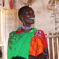 Community member from Kimanjo, Kenya dressed in traditional wear, standing up and talking.
