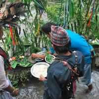 People perform a ceremony beside a river.