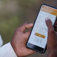 A close-up of a hand holding a mobile phone on which screen is an orange form, titled CRISP-M and options to select.