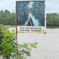 Sign by river reads: protect your town from flood, do not damage your mangrove